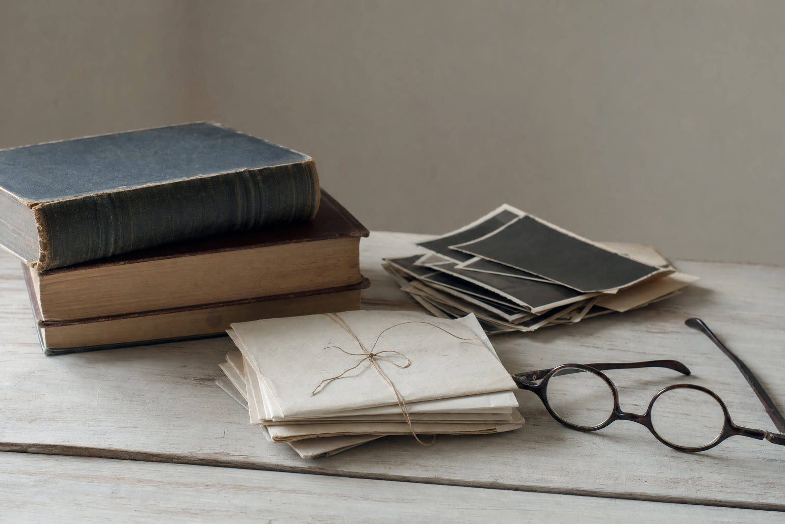 A stack of worn hardback books resting on a windowsill in daylight