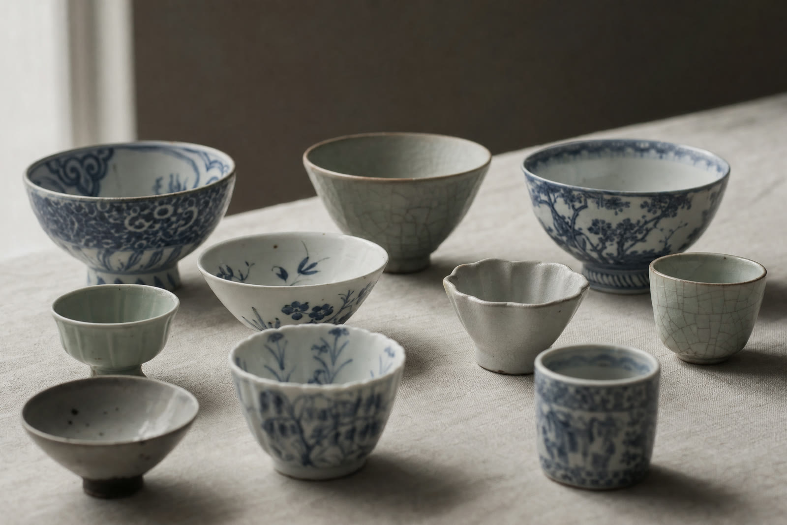 Rows of patterned porcelain cups and saucers arranged on lace-edged shelves