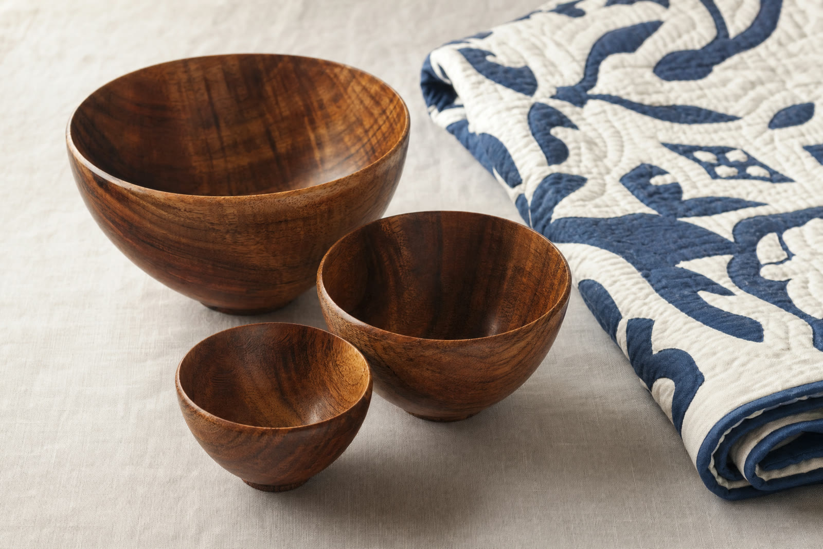 Turned wooden bowls and plates stacked on a pale surface